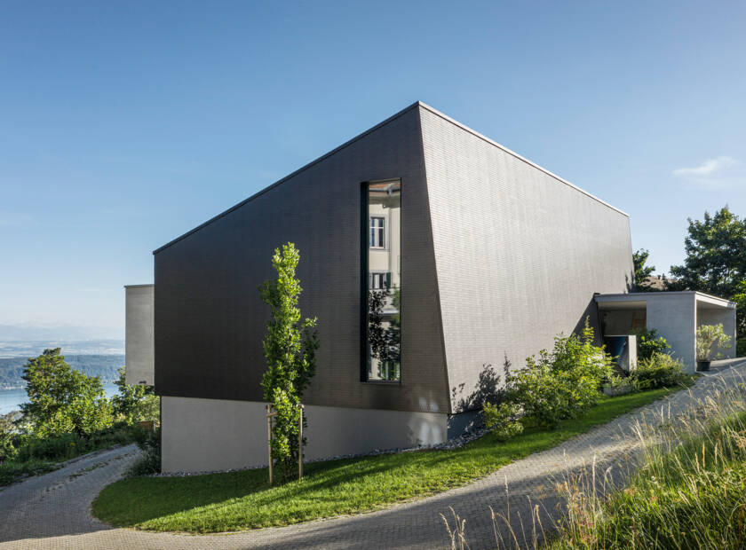 Haus wie ein schwarzer Kubus mit integriertem Balkon Einfamilienhaus Preles, Schweiz